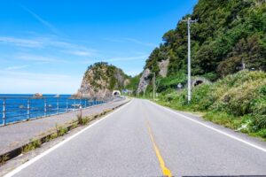 青い海と岩壁に沿って延びる海岸道路