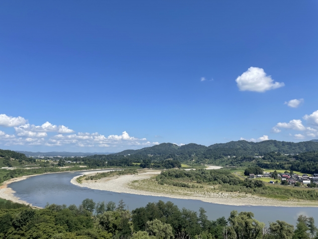 青空と山々に囲まれた信濃川の雄大な風景