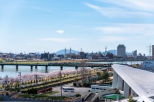 桜並木と電車を望む信濃川沿いの新潟市街地
