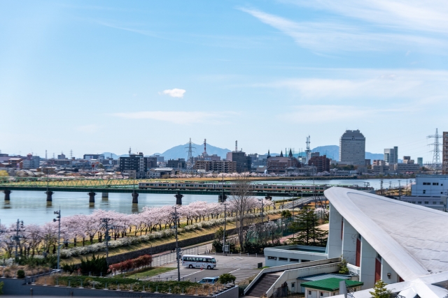 桜並木と電車を望む信濃川沿いの新潟市街地
